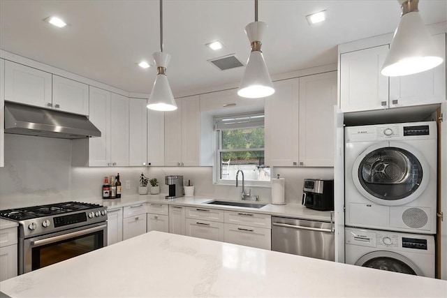 kitchen featuring stacked washer / dryer, white cabinetry, hanging light fixtures, and stainless steel appliances