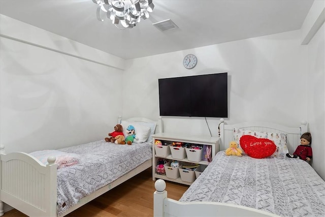 bedroom featuring hardwood / wood-style flooring and a chandelier