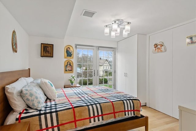 bedroom with light hardwood / wood-style floors and an inviting chandelier