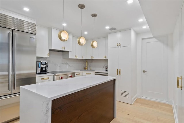 kitchen featuring a center island, decorative light fixtures, light hardwood / wood-style floors, white cabinetry, and stainless steel appliances