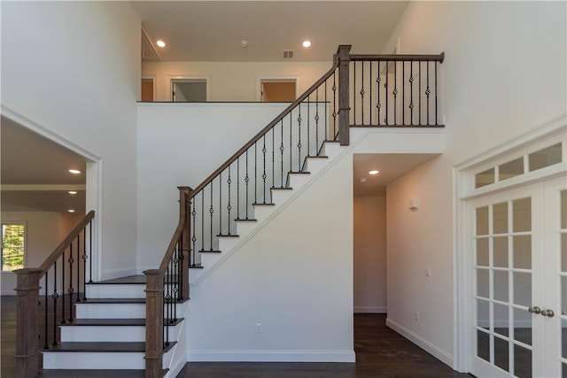 staircase with wood-type flooring and a high ceiling