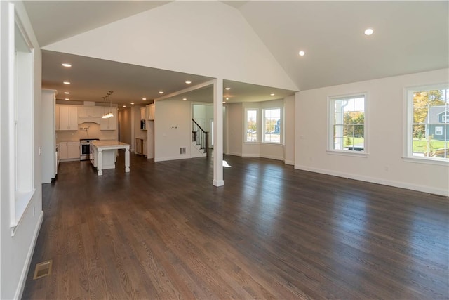 unfurnished living room featuring dark hardwood / wood-style flooring, high vaulted ceiling, and plenty of natural light