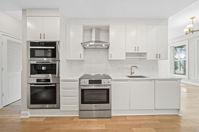 kitchen with sink, white cabinets, wall chimney exhaust hood, stainless steel appliances, and light hardwood / wood-style flooring