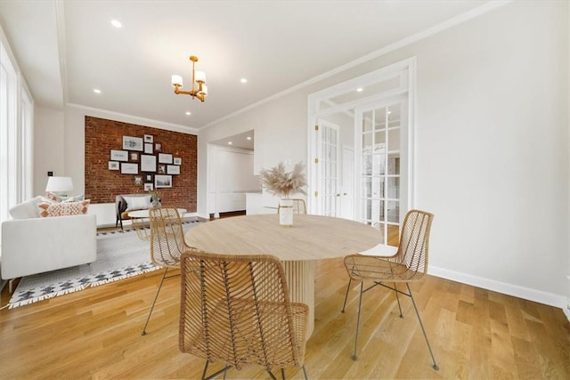 dining space with an inviting chandelier, crown molding, brick wall, and light wood-type flooring