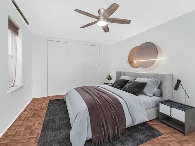 bedroom featuring ceiling fan, parquet flooring, and a closet