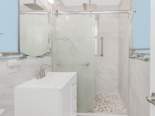 bathroom with tasteful backsplash, a shower with door, vanity, and tile walls