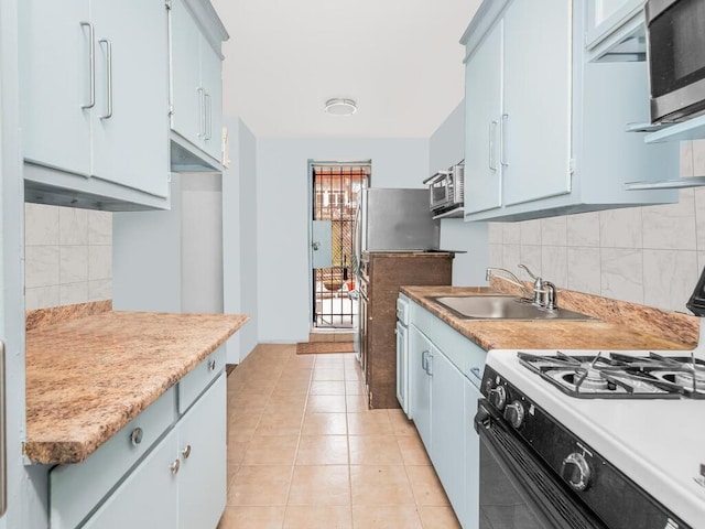 kitchen with backsplash, gas range, blue cabinets, sink, and light tile patterned floors