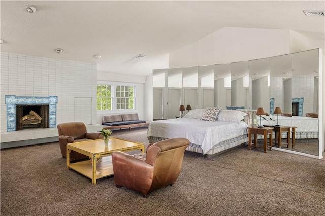 bedroom featuring dark carpet, lofted ceiling, and a brick fireplace