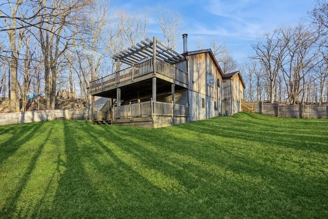 rear view of house with fence, a deck, and a yard