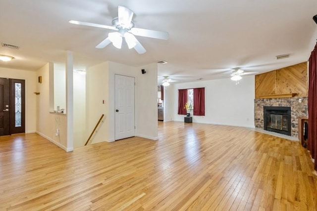 unfurnished living room featuring baseboards, visible vents, a ceiling fan, a stone fireplace, and light wood-style floors