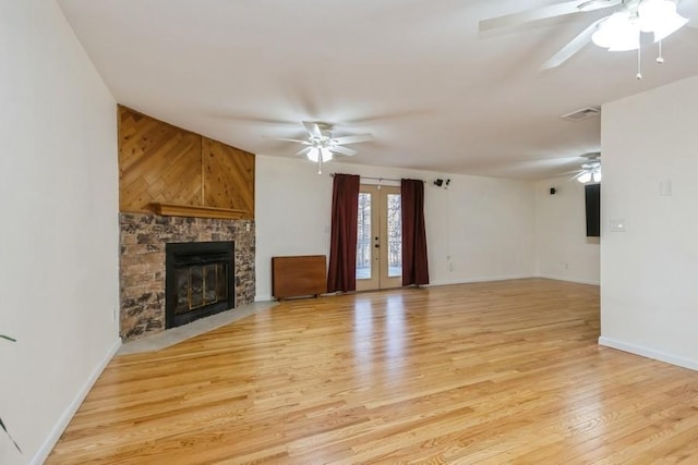 unfurnished living room with light wood-style floors, visible vents, a ceiling fan, and a stone fireplace