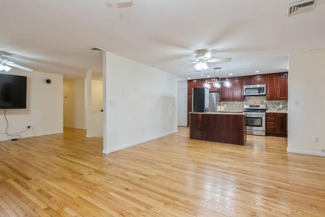 kitchen with visible vents, appliances with stainless steel finishes, open floor plan, and a ceiling fan