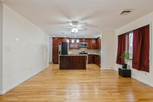 kitchen featuring appliances with stainless steel finishes, light wood-style flooring, backsplash, and visible vents