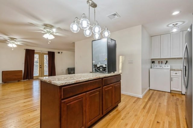 kitchen featuring visible vents, freestanding refrigerator, light wood finished floors, and washer / dryer