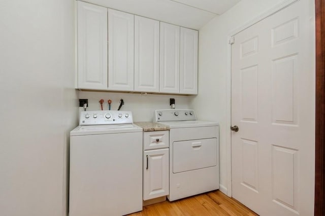 laundry area with light wood-type flooring, cabinet space, and washing machine and clothes dryer