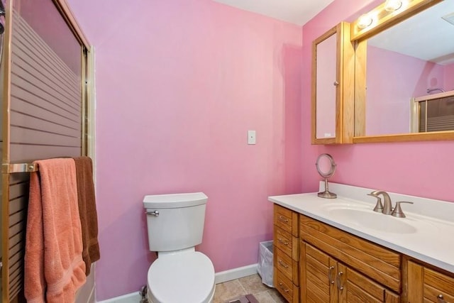 bathroom featuring toilet, a shower with shower door, baseboards, and vanity