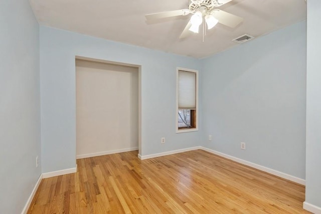 empty room featuring baseboards, visible vents, ceiling fan, and wood finished floors