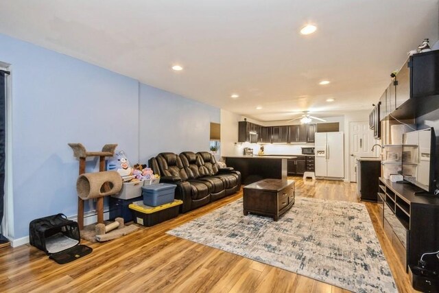 living room featuring ceiling fan, baseboards, light wood-style flooring, and recessed lighting