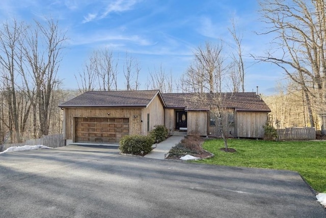 view of front of property with a garage, driveway, a front lawn, and fence