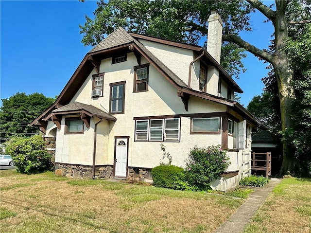 tudor-style house with a front lawn and cooling unit