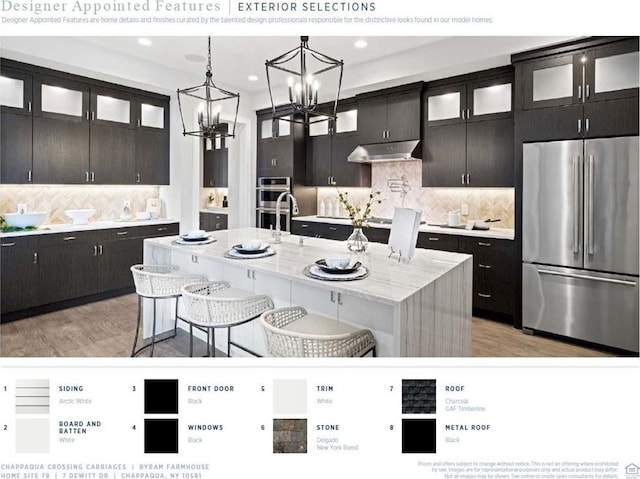 kitchen featuring a kitchen island with sink, decorative backsplash, appliances with stainless steel finishes, a notable chandelier, and a breakfast bar area