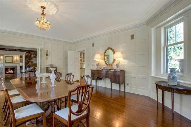 dining area featuring crown molding, dark wood-type flooring, and an inviting chandelier