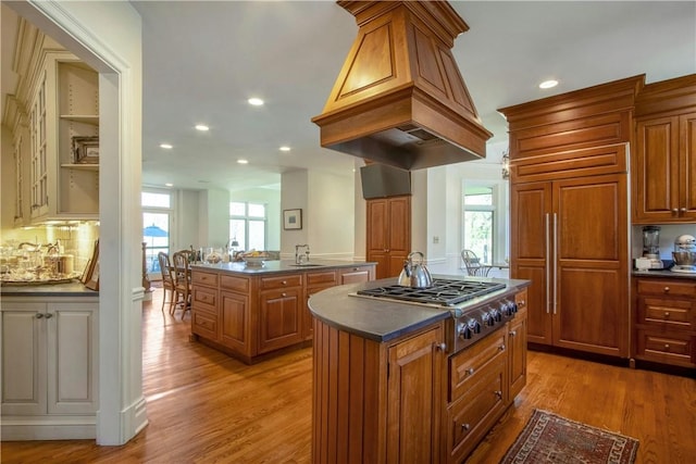 kitchen with light wood-type flooring, tasteful backsplash, sink, a center island, and stainless steel gas stovetop