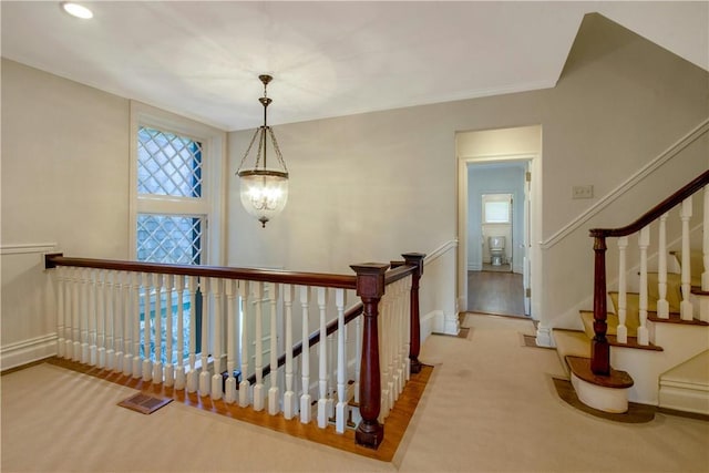 stairway featuring carpet flooring and a chandelier