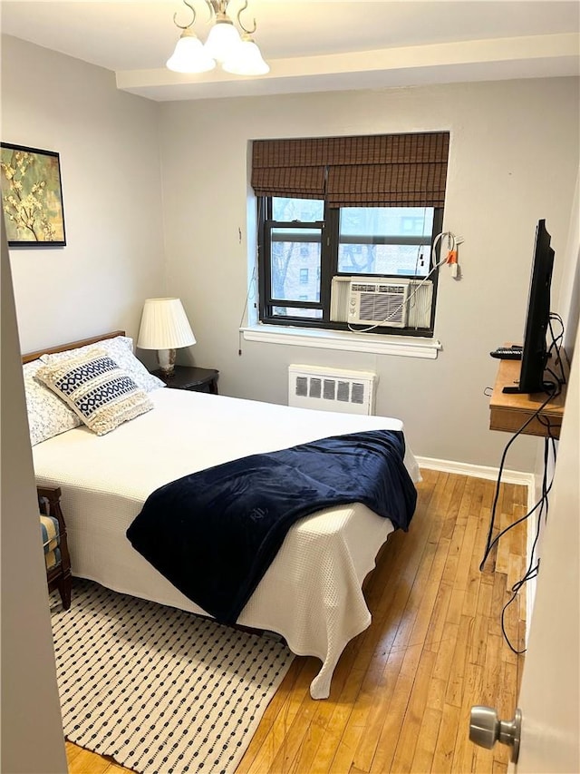 bedroom with hardwood / wood-style floors, cooling unit, radiator, and an inviting chandelier