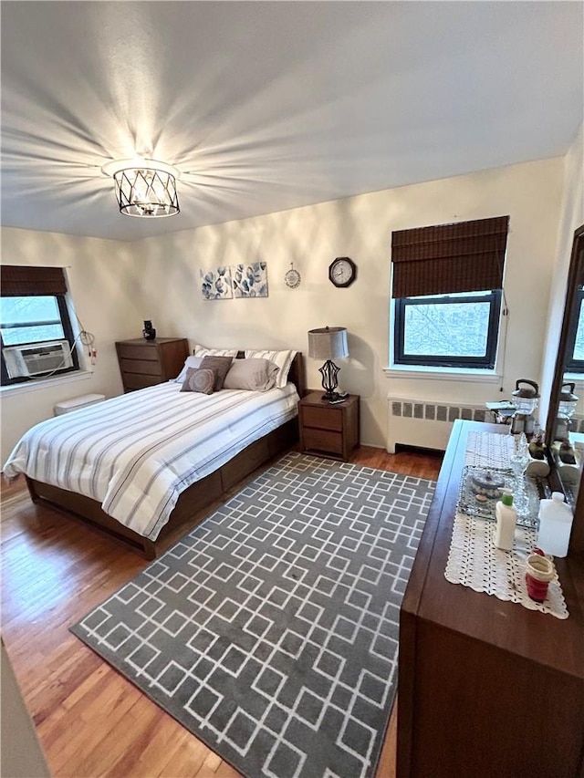 bedroom with radiator heating unit, dark hardwood / wood-style flooring, and cooling unit