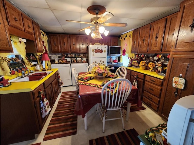 kitchen with ceiling fan, sink, white refrigerator, a paneled ceiling, and washer and dryer