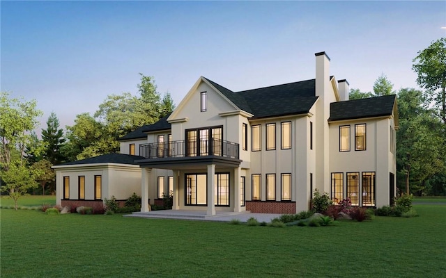 rear view of house with a patio, a balcony, and a lawn