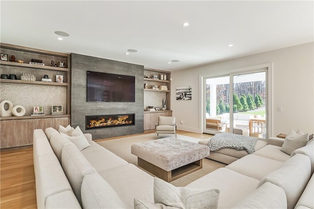 living room with a tile fireplace and light wood-type flooring