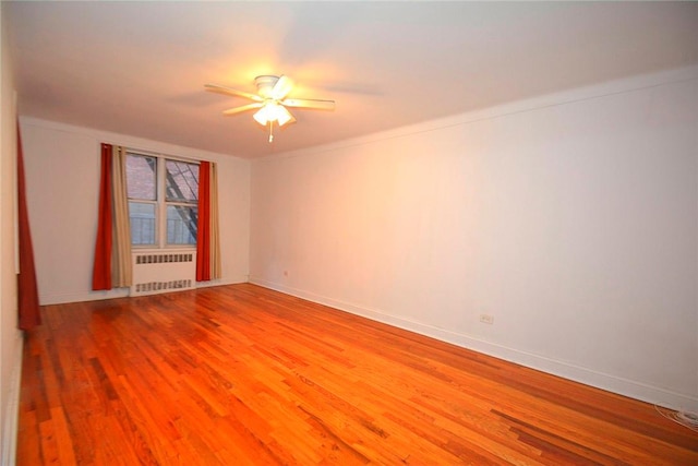 empty room with radiator heating unit, hardwood / wood-style flooring, and ceiling fan