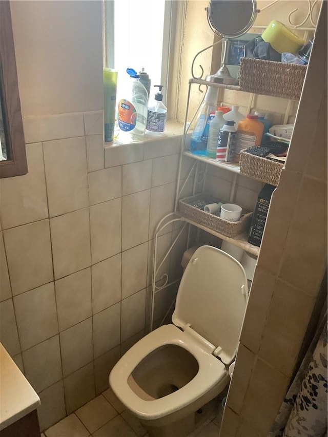 bathroom featuring tile patterned floors, toilet, and tile walls