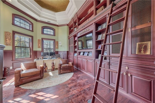 living area with hardwood / wood-style floors, a tray ceiling, crown molding, and a high ceiling