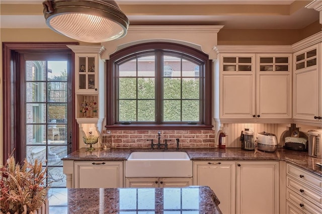 kitchen featuring white cabinetry, dark stone counters, and sink