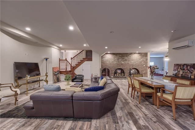 living room with a fireplace, hardwood / wood-style floors, a wall unit AC, and brick wall