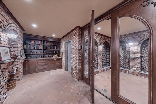 wine room with light tile patterned floors, crown molding, brick wall, and bar area