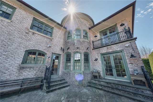 view of exterior entry featuring french doors and a balcony