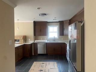 kitchen with crown molding, sink, dark tile patterned floors, and stainless steel appliances