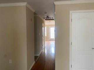 corridor with hardwood / wood-style floors and ornamental molding