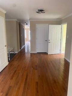 hallway with dark wood-type flooring and ornamental molding