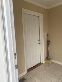 entryway featuring light tile patterned flooring and ornamental molding