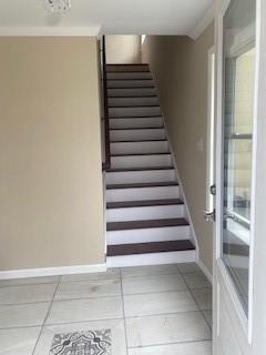 staircase featuring tile patterned flooring and crown molding