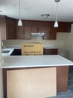 kitchen featuring decorative light fixtures, dark tile patterned flooring, and sink