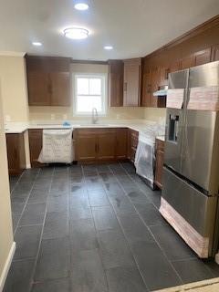 kitchen with stainless steel fridge, sink, white dishwasher, and range hood