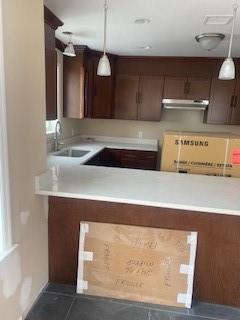 kitchen with dark tile patterned flooring, decorative light fixtures, dark brown cabinets, and sink