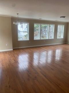 unfurnished room featuring hardwood / wood-style flooring, ornamental molding, and an inviting chandelier