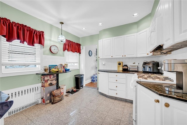 kitchen with radiator, gas range gas stove, white cabinets, and hanging light fixtures